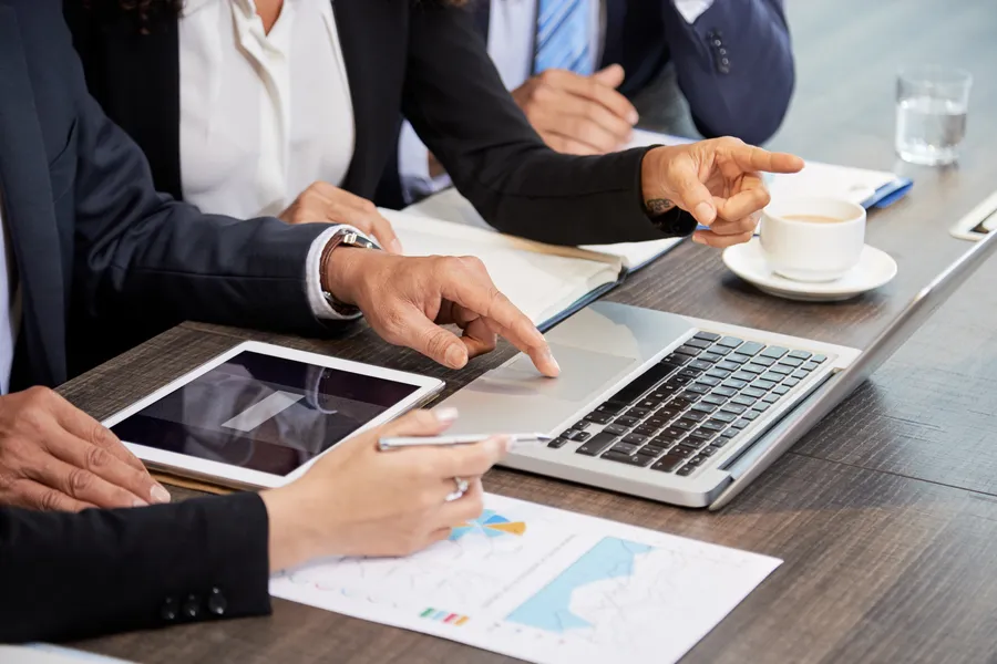 crop-colleagues-using-laptop-table